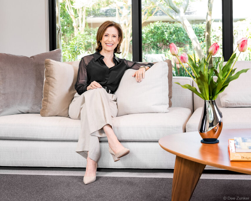 Female realtor seated on a light gray sofa in a modern living room setting for her branding portfolio.
