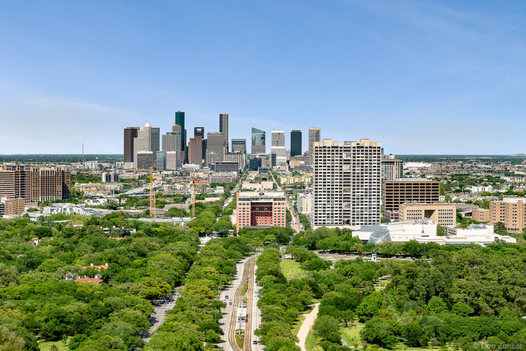 Sunny aerial view looking north over the Texas Medical Center district with the Downtown Houston skyline in the background.