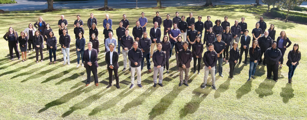 Aerial drone photo of a large corporate team group posed outdoors on a green lawn in Houston, Texas.