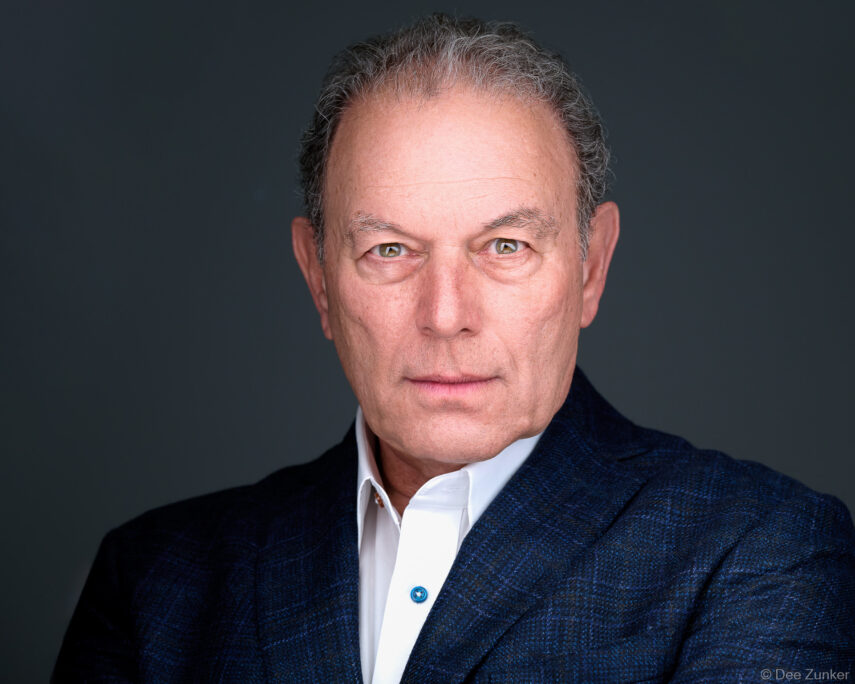 Male executive in navy blazer and white shirt poses for a professional corporate studio headshot against a gray background in Houston.