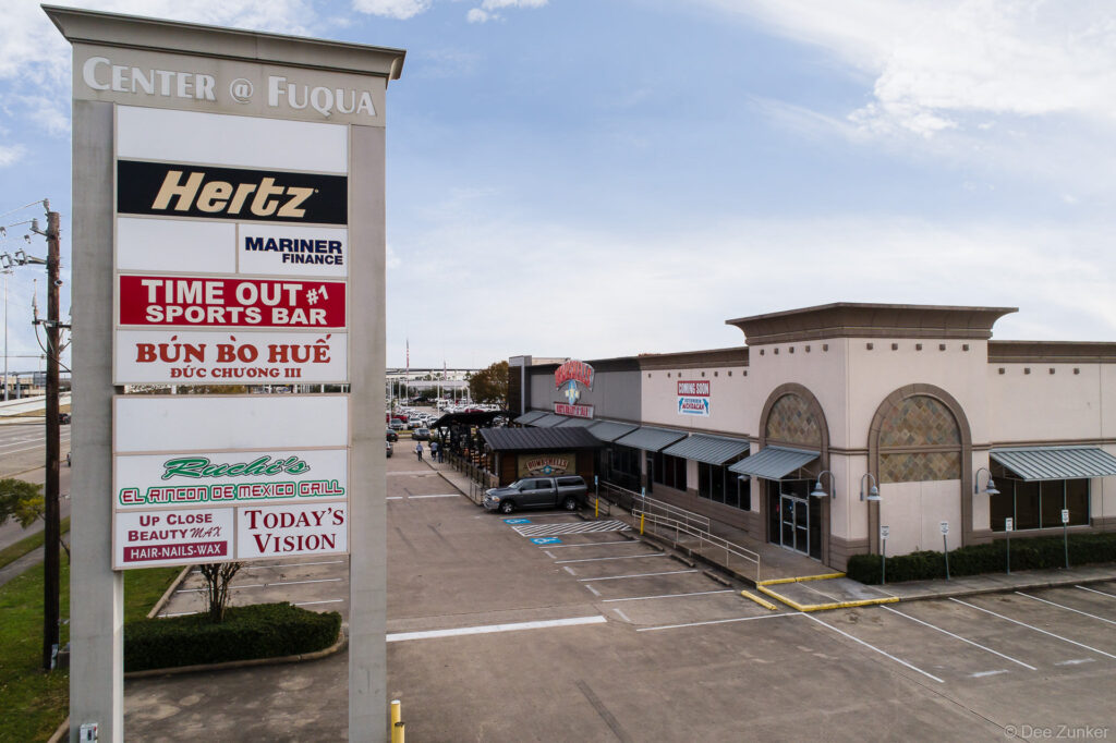 Drone aerial photo of Center at Fuqua shopping strip in Houston TX showing tenant signage and parking lot.