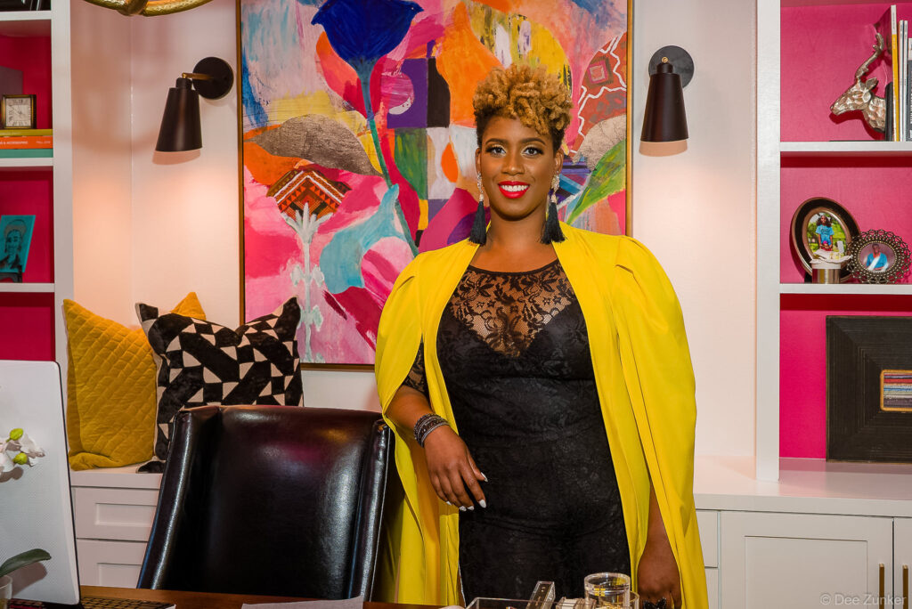 Houston interior designer in yellow cape dress posing confidently in a vibrant pink and white styled home office for branding headshots