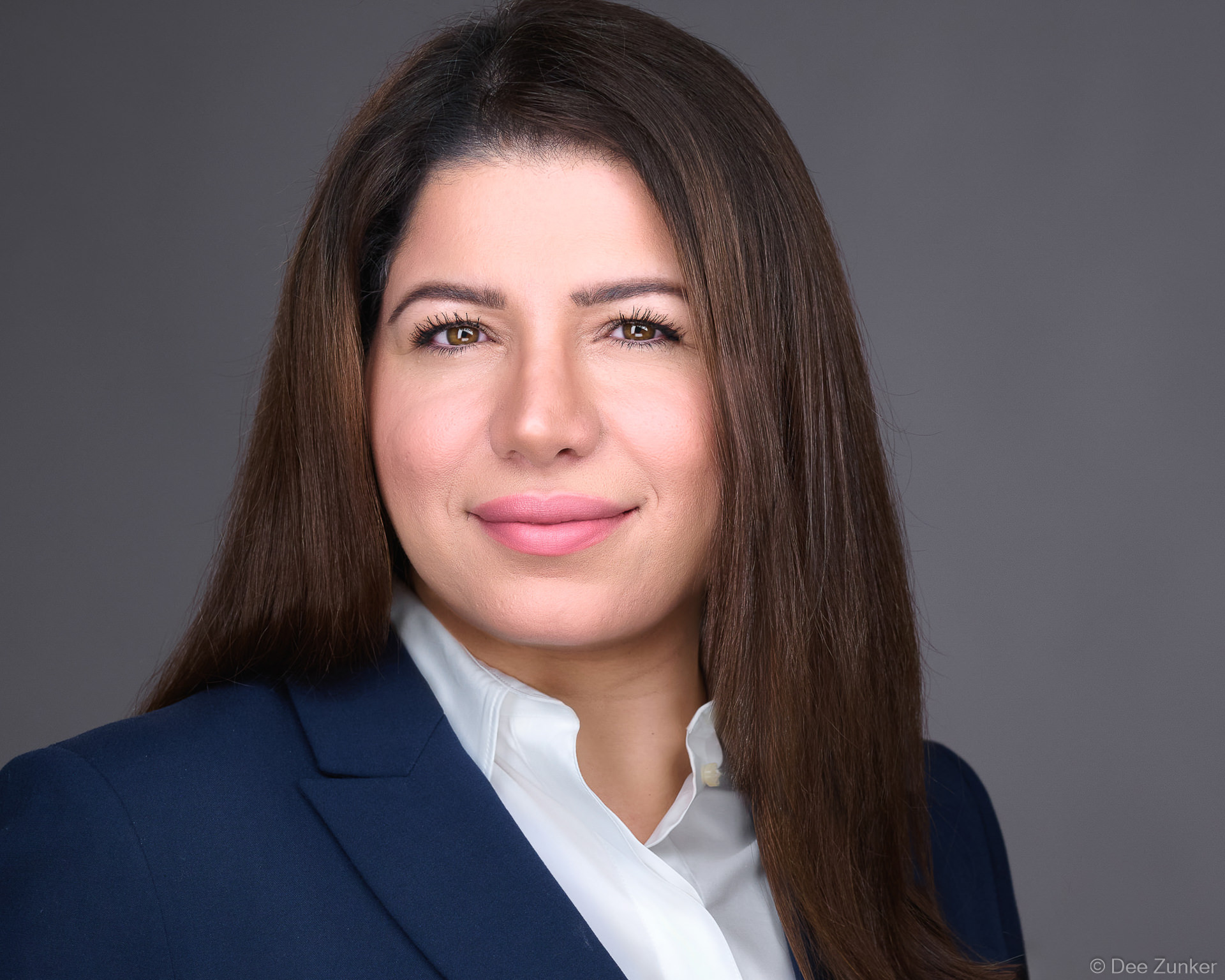 Female attorney studio headshot on gray background, navy blazer and white blouse, professional corporate portrait, Houston, TX.