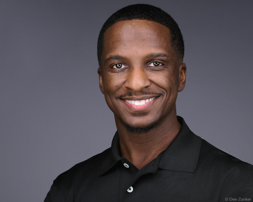Professional corporate headshot of a smiling male construction executive against a gray studio background, photographed in Houston, TX.