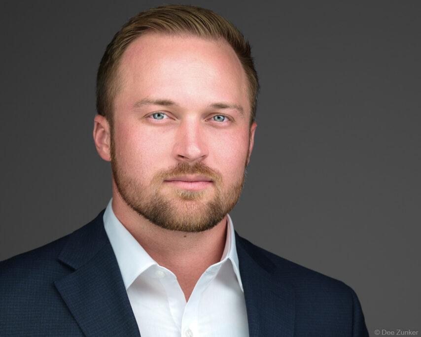 Professional male executive studio headshot, navy blazer, white shirt, gray background, corporate portrait photography, Houston, TX.