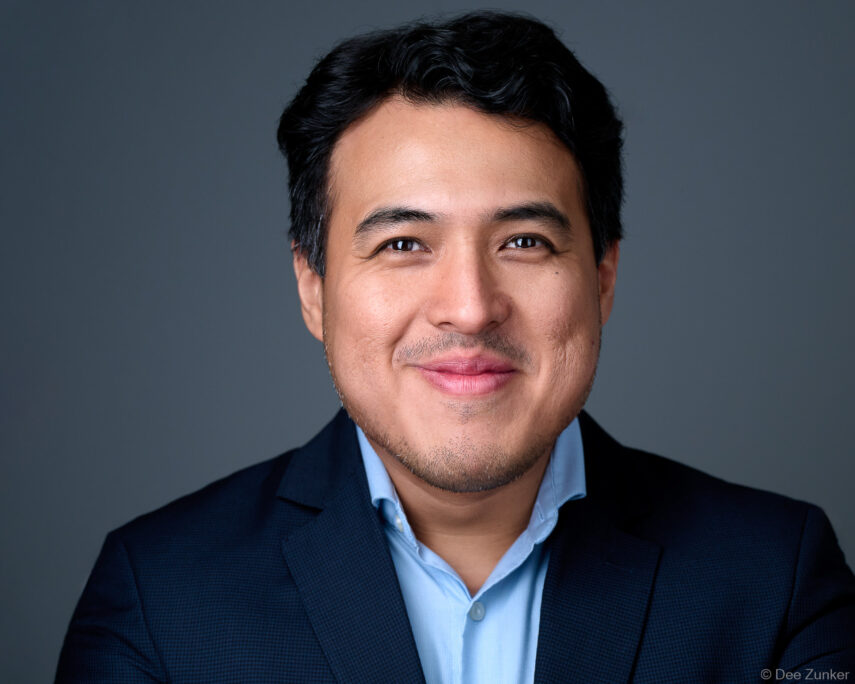 Professional male executive studio headshot on gray background, dark blazer and light blue shirt, Houston corporate portrait photography.