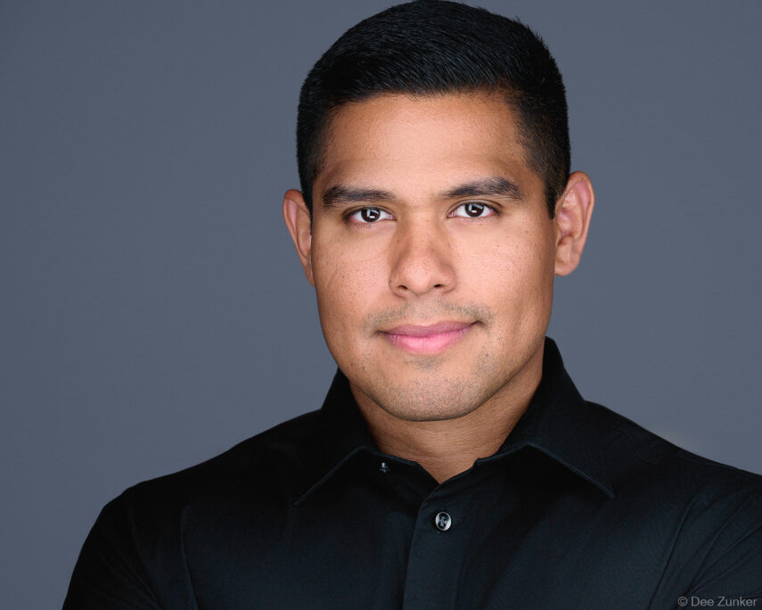 Male oil and gas industry professional in black shirt poses for corporate studio headshot against gray background in Houston, TX.