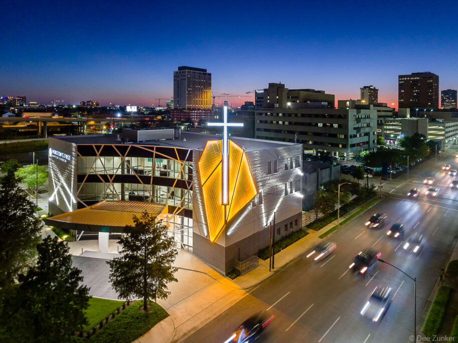 Aerial drone photo of the Houston First Baptist Downtown campus at night, showcasing the unique architectural lighting design.