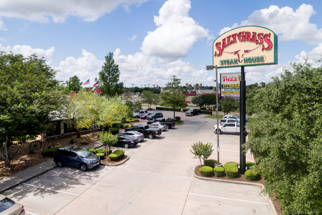 Aerial view of Saltgrass Steak House exterior and parking lot on Mason Road in Katy, TX, with retail signage visible in background photographed for land developer.
