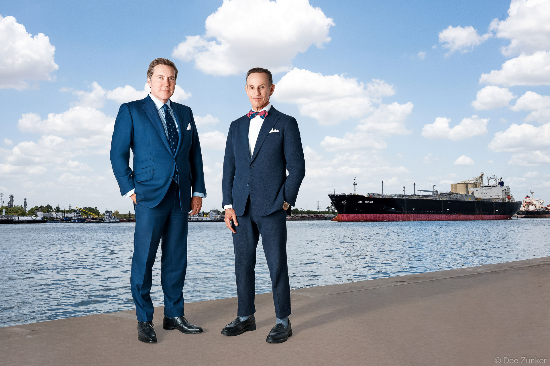 Two Houston lawyers in navy suits pose for corporate headshots on the Ship Channel waterfront with an LNG tanker docked behind them. Composited the 2 images with AI.