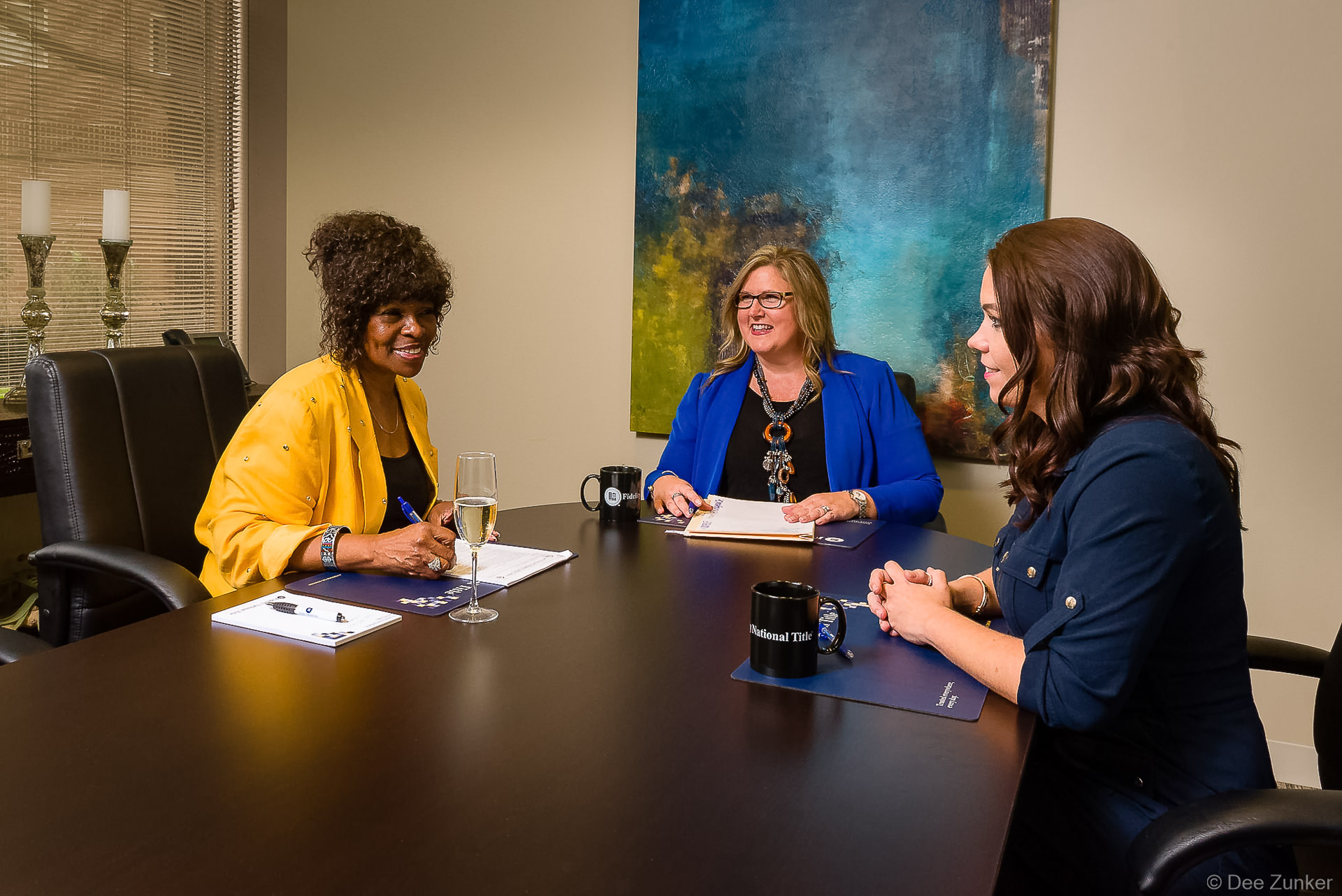Three professional women discussing documents at a conference table during a financial firm branding lifestyle photo session in Houston