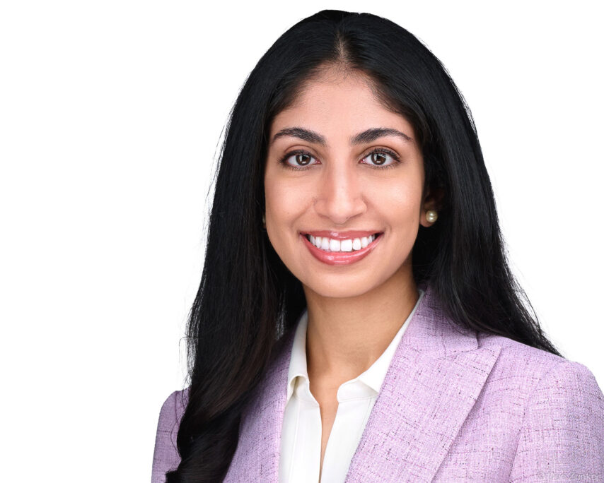 Smiling woman in lavender blazer and pearl earrings, professional corporate headshot for dermatology staff, Houston TX.