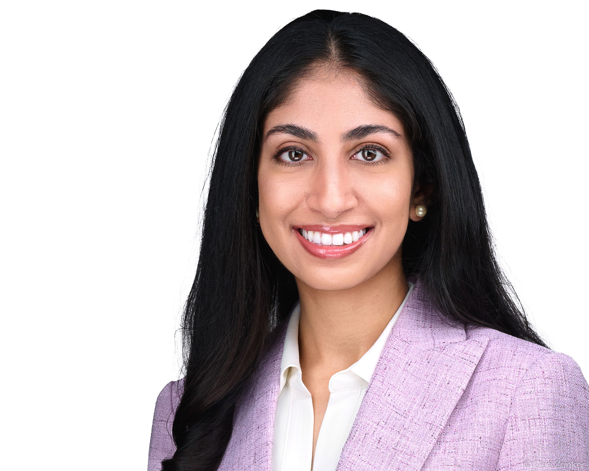 Smiling woman in lavender blazer and pearl earrings, professional corporate headshot for dermatology staff, Houston TX.