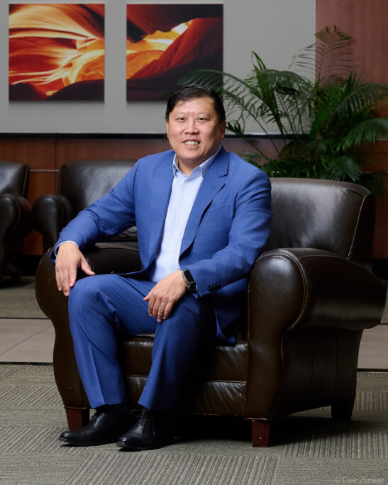 Male executive in blue suit seated in leather armchair for Piney Point OMS corporate staff portrait, Houston TX.