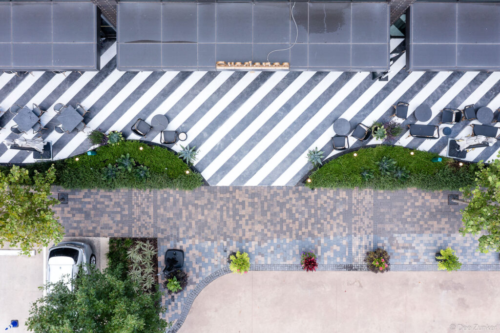 Overhead drone photo of Credence Landscaping Memorial City Houston showing striped patio seating, manicured planters, and decorative brick walkway.