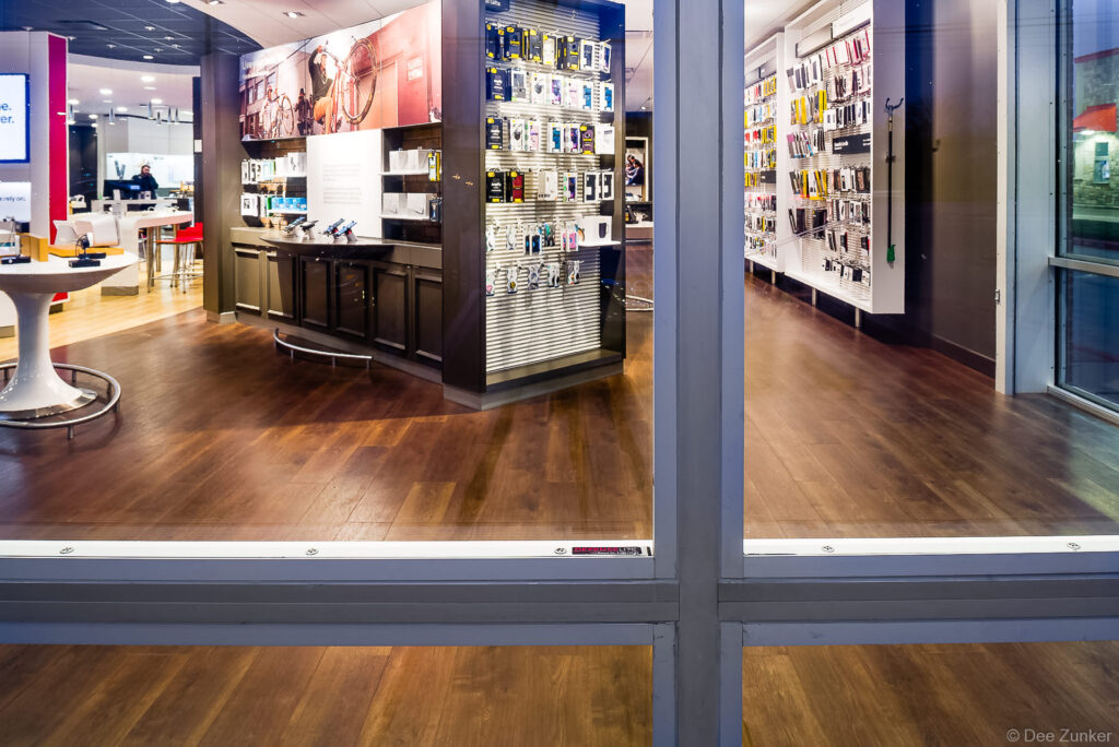 Houston retail store interior photographed through architectural glass windows showing phone accessories displays and hardwood floors.