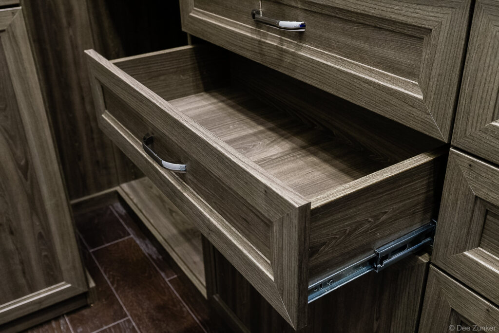 Open wood grain dresser drawer with chrome pull hardware, shot for Houston closet product photography portfolio by Dee Zunker.