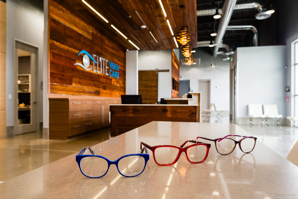 Three colorful eyeglass frames displayed on a counter inside Elite Vision Care optometry office, shot by Houston commercial photographer.