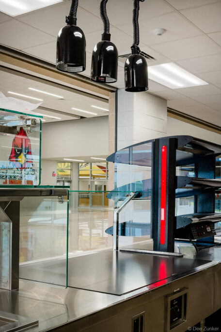 Stainless steel cafeteria serving counter with heat lamps and pizza warmer at a Houston junior high school cafeteria.