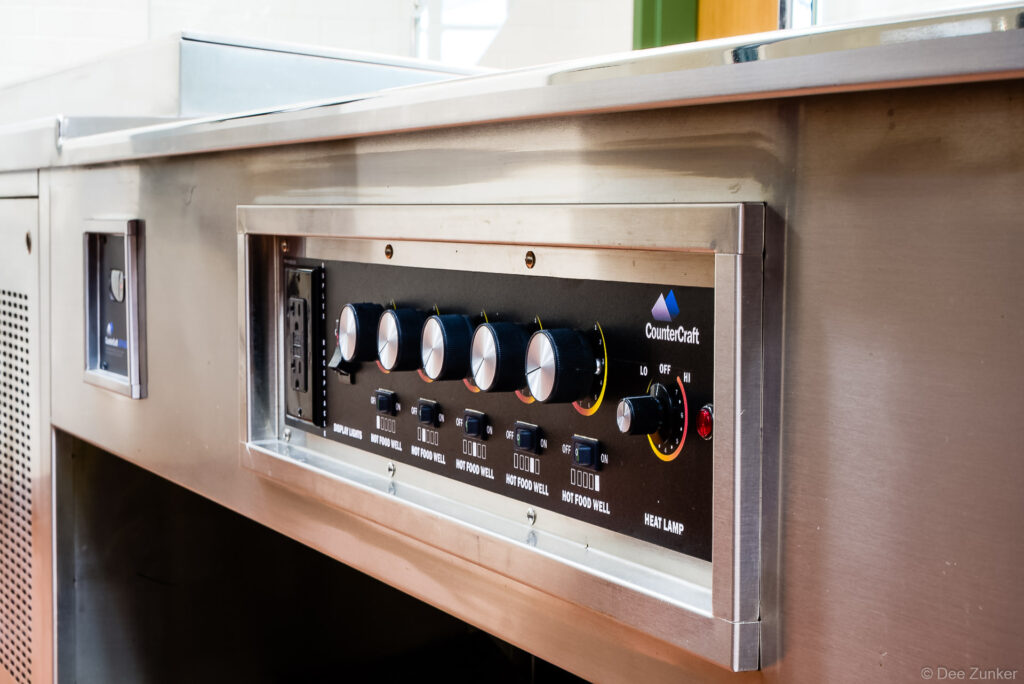 CounterCraft stainless steel food service counter control panel with hot food well knobs and heat lamp dial, Houston commercial product photography.