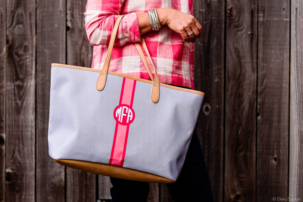 Woman holding a monogrammed blue seersucker tote bag with pink stripe, lifestyle product photography by Dee Zunker Photography Houston.