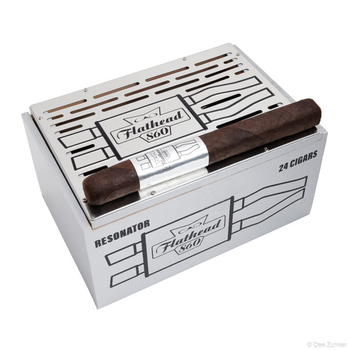 CAO Flathead 860 Resonator cigar box containing 24 cigars with one cigar displayed on top, white background product photography.