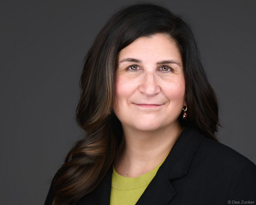 Female attorney corporate headshot on gray background, studio portrait by Houston commercial photographer Dee Zunker Photography.