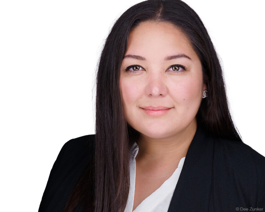 Professional corporate headshot of a woman in a black blazer and white blouse, photographed against a clean white studio background in Houston.