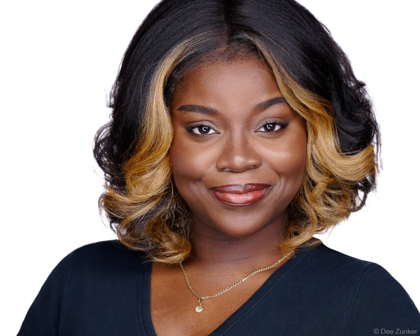 Woman in black top with ombre highlights smiles in a studio corporate headshot on a white background, Houston TX.