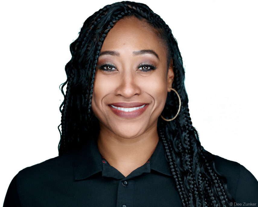 Smiling professional woman with box braids poses for a corporate headshot on a white background, Houston studio photography.