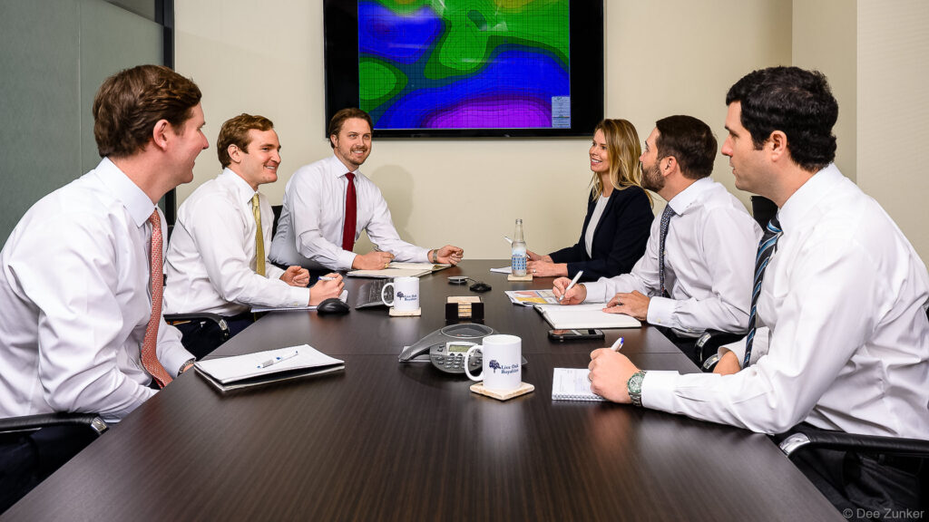 Six Live professionals in business attire collaborate around a conference table in a Houston office boardroom.