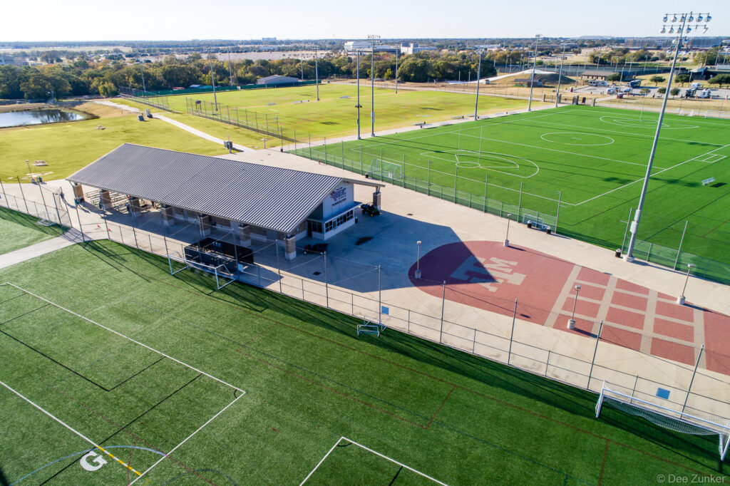 Aerial drone view of Texas A&M Penberthy athletic complex showing soccer fields, track, and training facility in Texas.