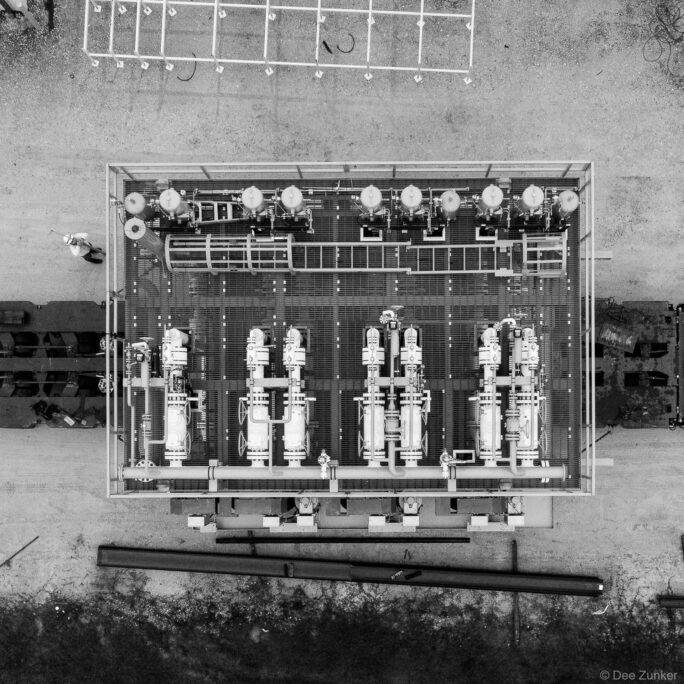 Aerial drone photo of industrial pump skid transport unit with valves and piping, shot from directly overhead in Houston TX.