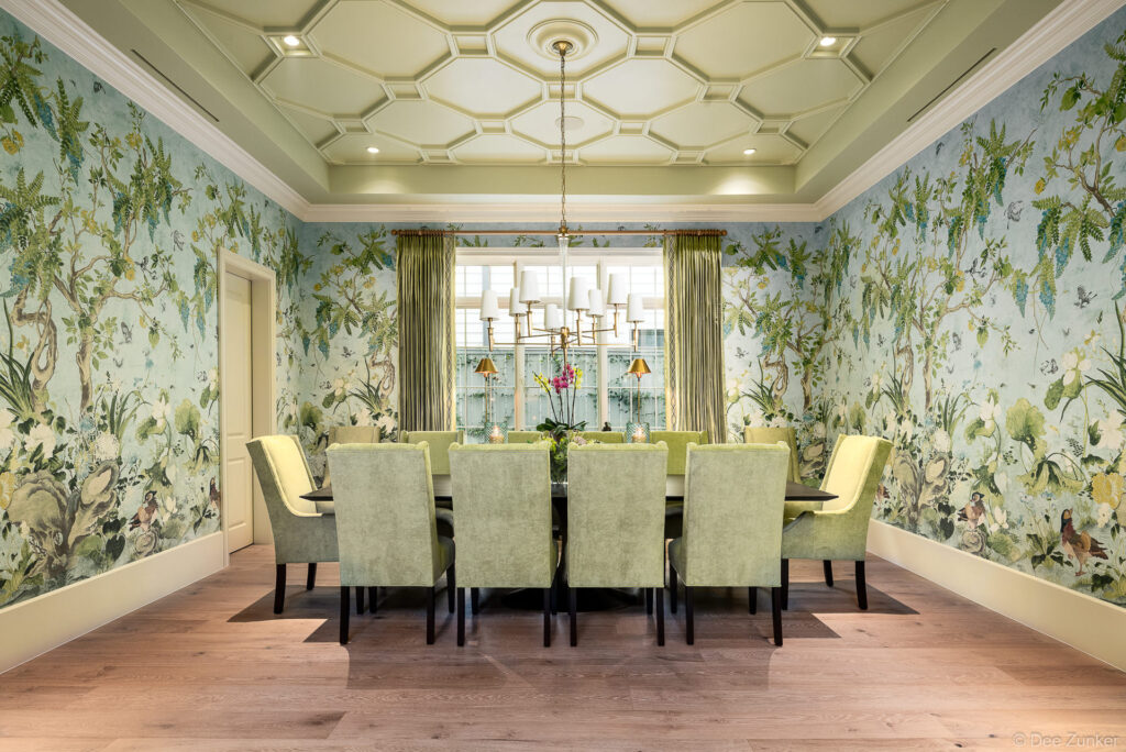 Formal dining room with floor-to-ceiling chinoiserie wallpaper, green upholstered chairs, coffered ceiling, and brass chandelier, photographed by Houston architectural photographer.