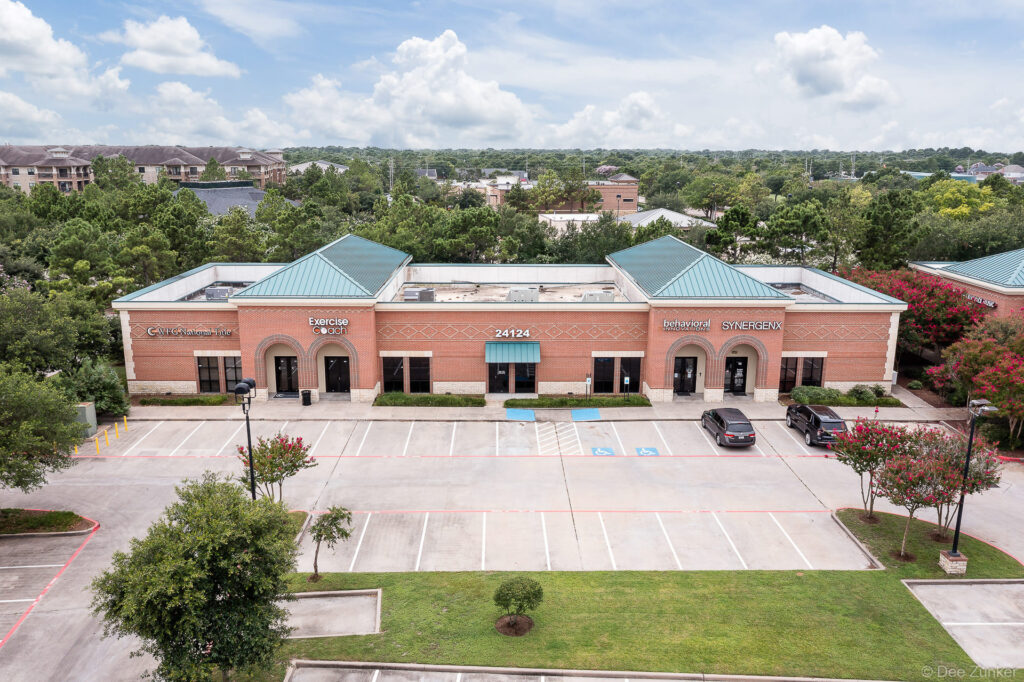Drone aerial photo of brick commercial strip center, Katy TX, with teal metal roofs and parking lot.