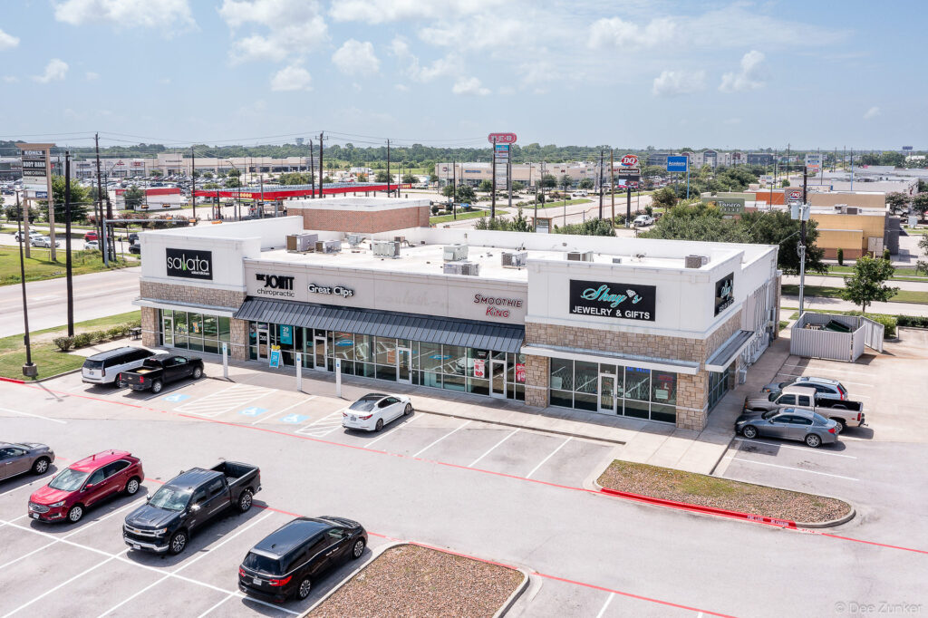 Drone aerial photo of a multi-tenant retail strip center on Garth Road Texas featuring a full parking lot and suburban commercial corridor.