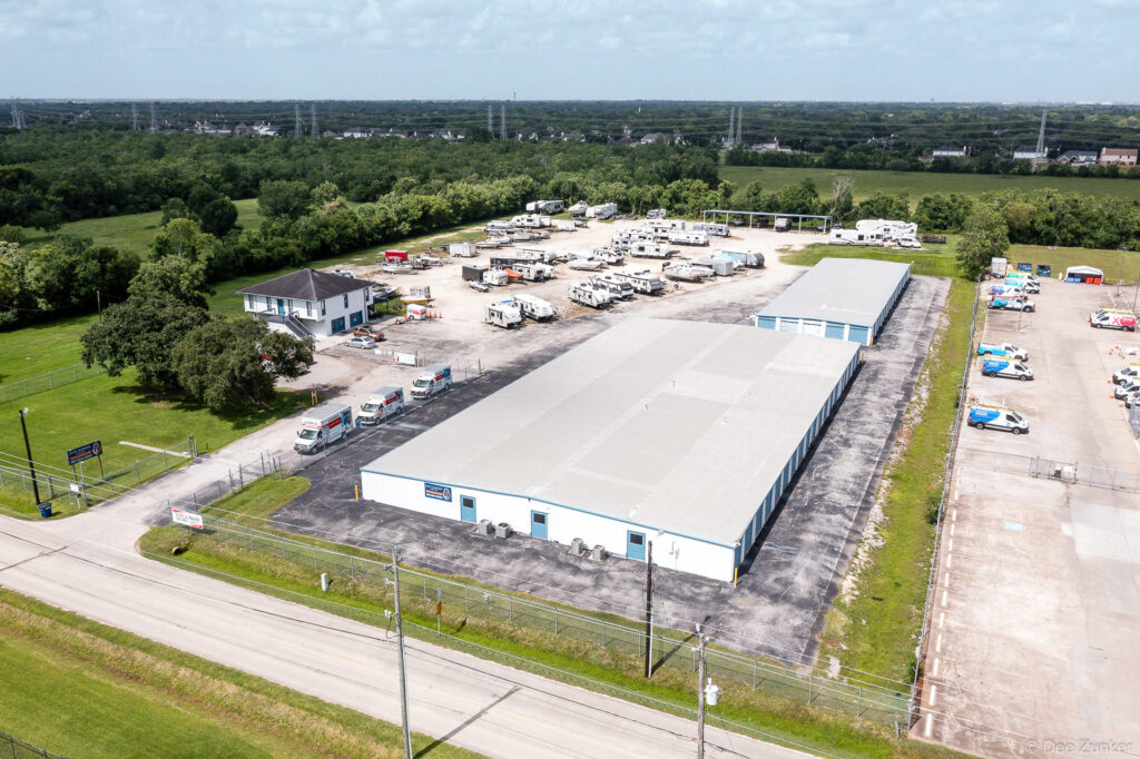 Drone aerial photo of a self-storage facility on Lawrence Road Houston showing indoor units, RV parking lot, and surrounding green landscape.