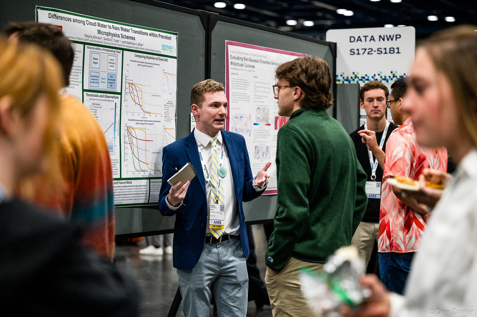 Young researcher in blue blazer presents atmospheric science poster on cloud microphysics at AMS conference poster session.