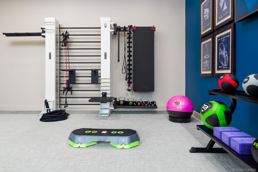 Well-equipped apartment fitness center featuring wall-mounted rack, kettlebells, medicine balls, stability ball, and step platform in Houston.