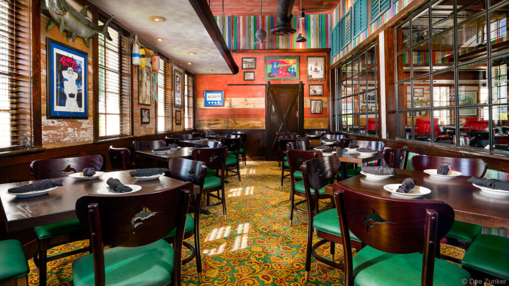 Colorful dining room interior at Babins Seafood House in Katy TX featuring green upholstered chairs dark wood tables and eclectic Gulf Coast decor