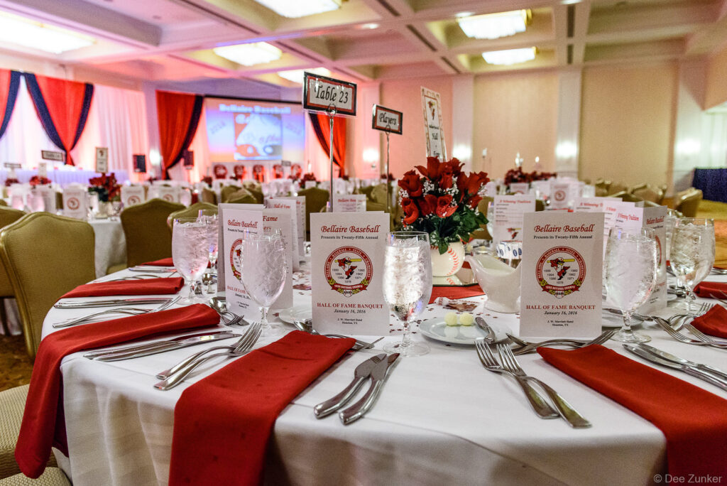 Elegantly set banquet table with red napkins, crystal glassware, and Hall of Fame programs at a Houston baseball awards dinner.