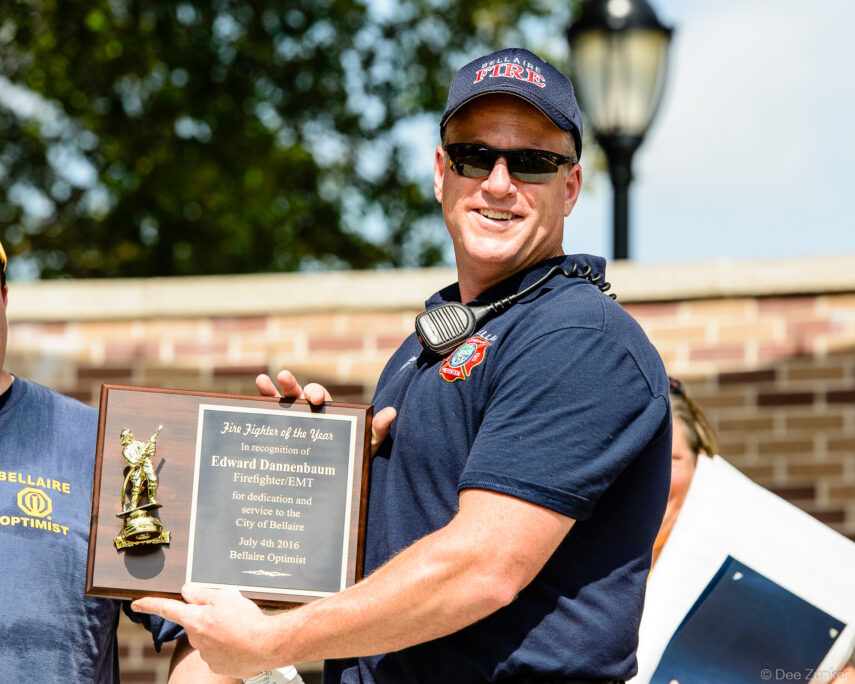 Bellaire firefighter and EMT proudly holds Fire Fighter of the Year award plaque at Fourth of July parade, Houston, TX.