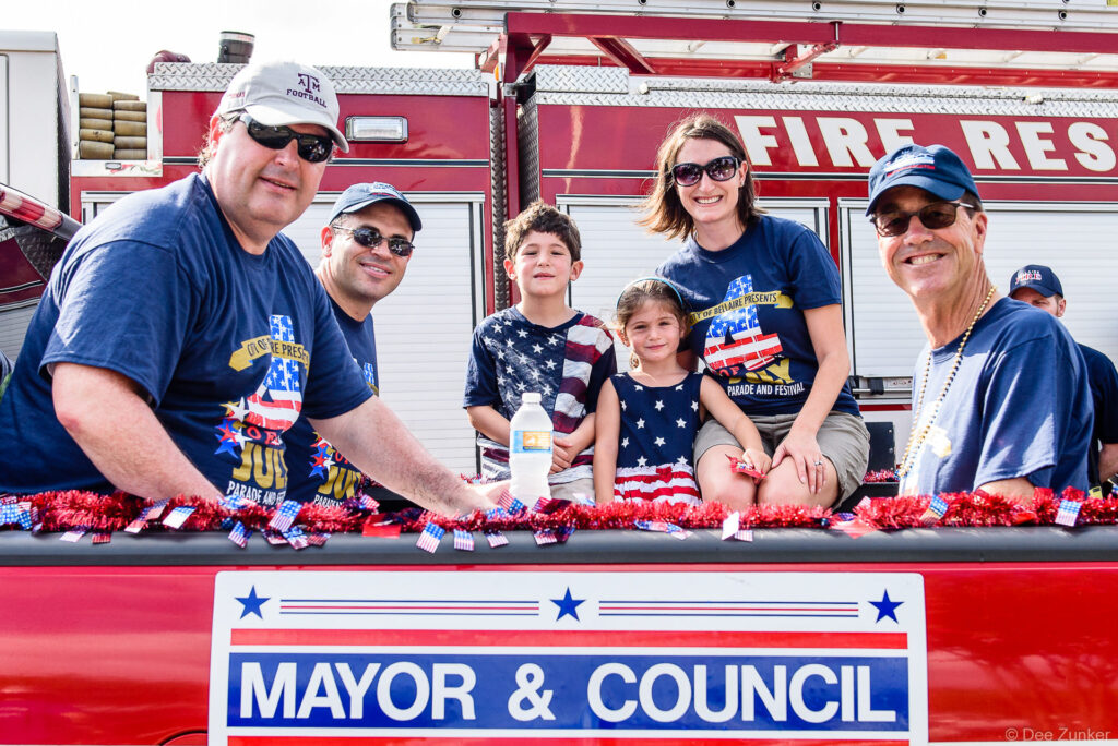 Mayor and council members with families on decorated parade float at Bellaire Fourth of July Parade 2016, Houston TX.