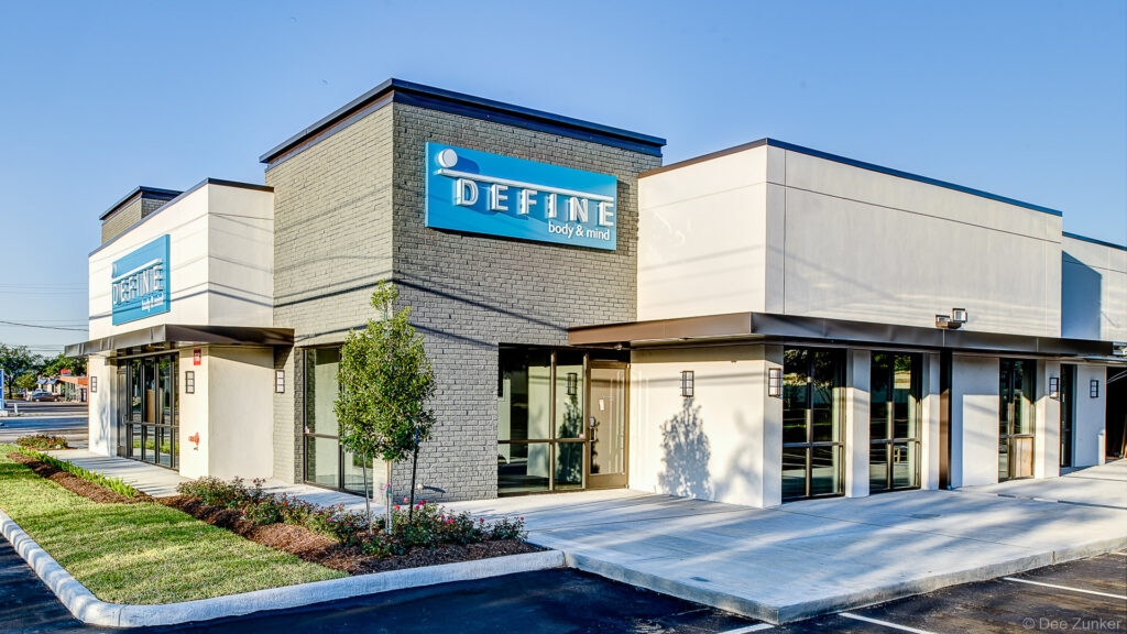 Modern commercial fitness studio exterior in Bellaire Houston featuring gray brick facade, blue signage, and contemporary retail architecture