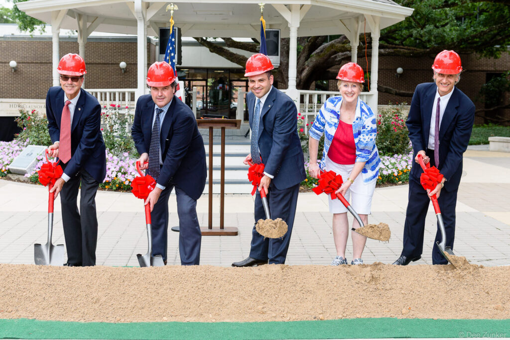 Five officials in red hard hats pose with decorated shovels at Bellaire municipal facilities groundbreaking ceremony Texas