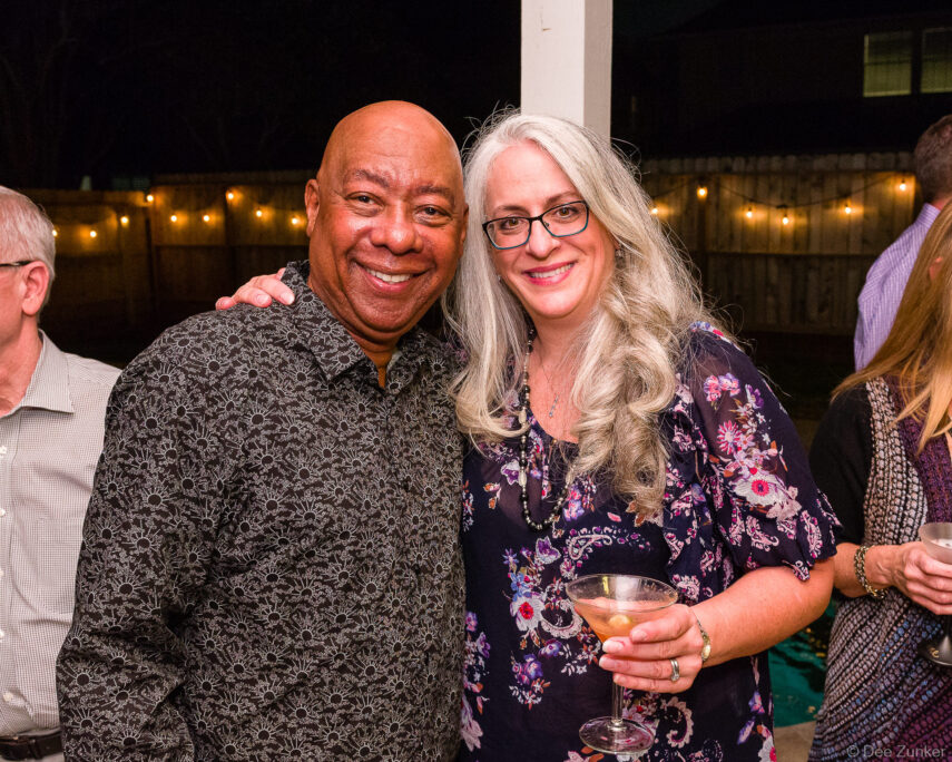 Two smiling corporate event guests pose with a martini cocktail at an outdoor Bellaire Parks patrons party in Houston.