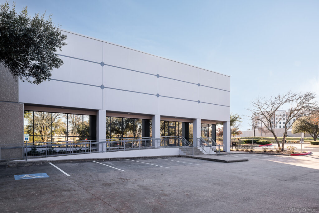Modern two-story commercial office building exterior at Brockton, Houston TX, featuring large storefront windows and surface parking lot.