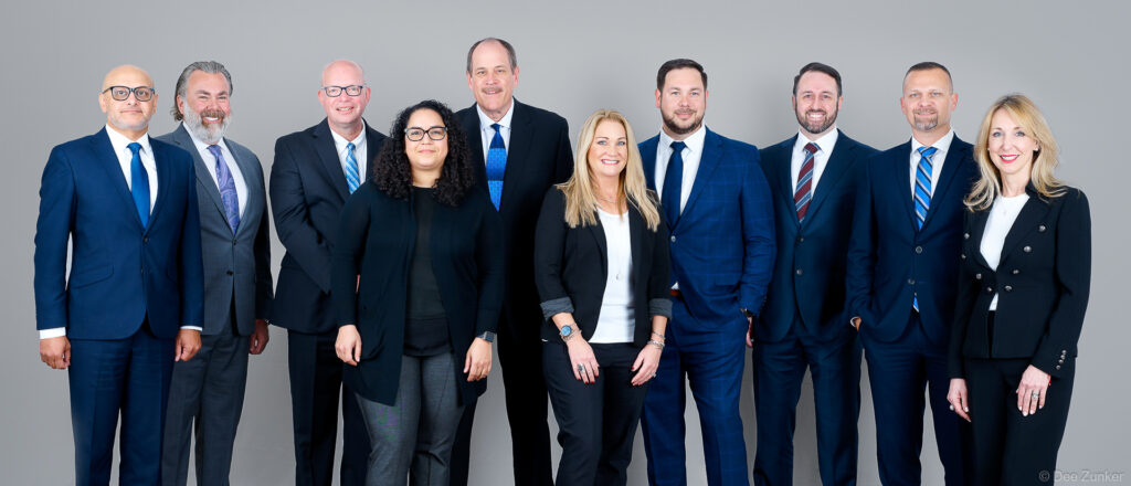 Ten business professionals in formal attire pose together for a corporate annual report group portrait, Houston