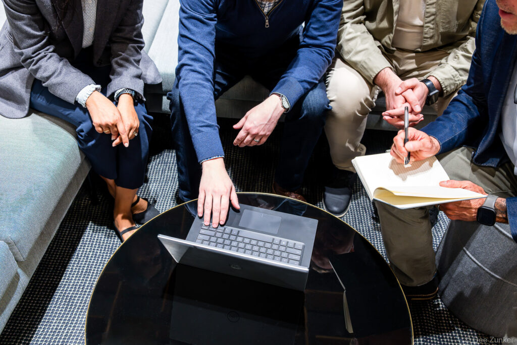 Overhead view of four professionals collaborating around a round table with a laptop and notepad during a corporate branding meeting in Houston.