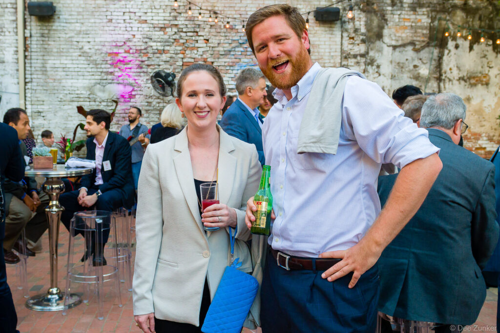 Two smiling corporate event attendees holding drinks at an outdoor brick courtyard venue in Houston, TX.